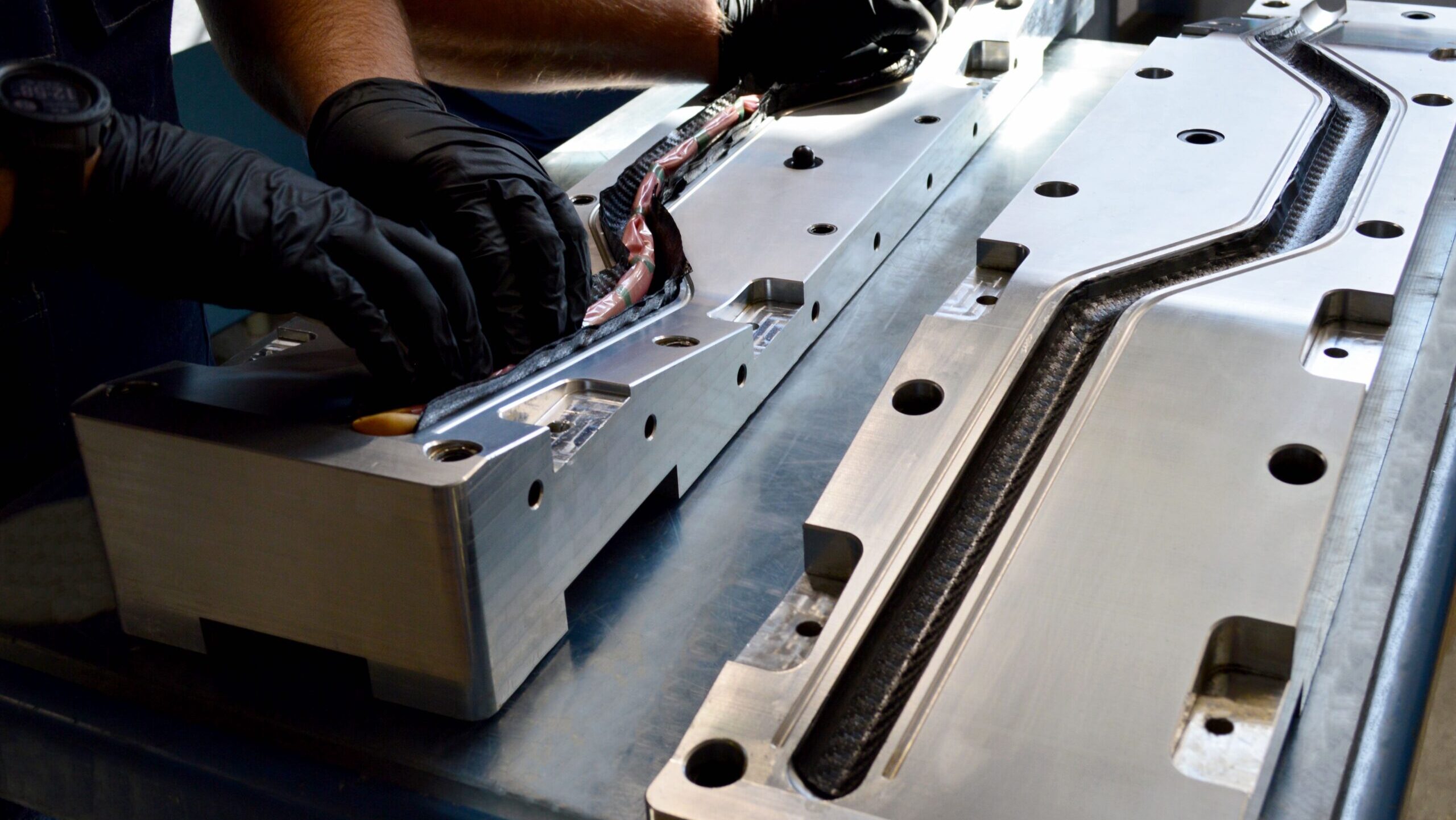 Custom mold for custom handlebars made out of carbon fiber, workers laying up material for bladder molding.